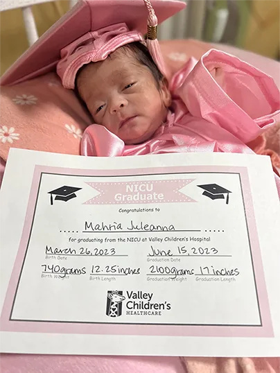 a tiny baby in pink with a birth certificate